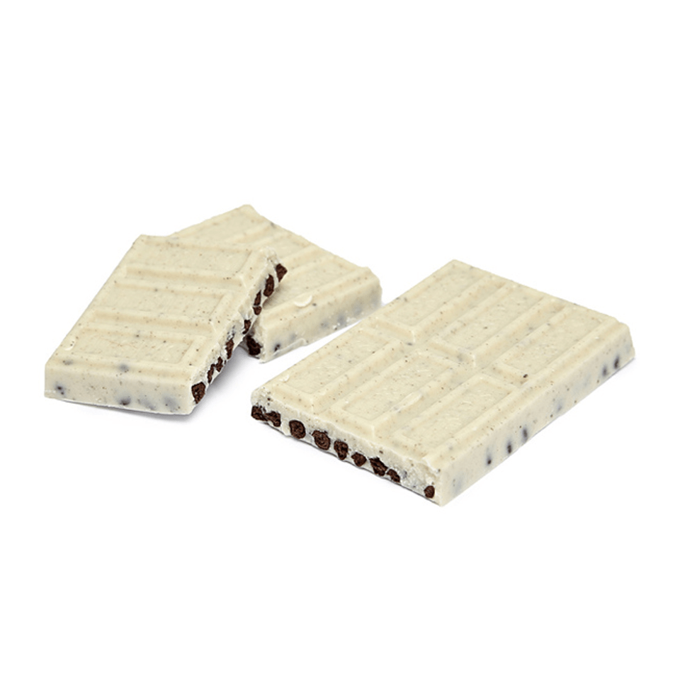 Des morceaux d’une tablette de chocolat blanc avec des morceaux de biscuits noirs, le tout sur fond blanc